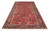 Angled full view of a red and blue hand-knotted Heriz wool rug on white