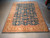 Full flat view of the teal and gold Ziegler design rug photographed on concrete