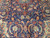 Ivory arabesque cartouches and red lotus blossoms drawn across the deep navy wool field