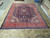 Full 10x13 Persian Mahal rug displayed flat on showroom floor showing red border symmetry