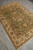 Angled floor view of Indian Chobi area rug, olive field framed by wide cream border