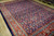Angled view of 9x13 semi-antique Persian rug showing navy field, rust border and wool pile