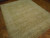 Angled floor view showing beige ivory border and soft golden field of this 8x10 wool rug