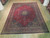 10x13 semi antique Tabriz rug displayed flat on light wood showroom floor, full medallion visible