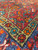 Angled detail of dense wool pile showing Herati lattice, olive guard stripe and orange blossoms