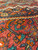 Low angle view across thick Kurdish wool pile with teal leaves and burnt orange accents
