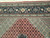 Border detail showing pale green minor bands, navy vine border and copper herati field