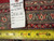 Reverse side of a hand-knotted rug with inventory tag and Stanley tape measure laid across