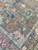 Close-up of sea green rosette and navy motifs scattered across the striated gray wool field