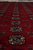 Close-up of the field, teal and salmon guls with black outlines on crimson wool
