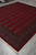 8 by 9 wool Bokhara rug at an angle, ivory fringe and dense pile visible