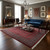 Red Bokhara rug anchoring a living room with blue chesterfield sofa, chandelier and dark hardwood floors