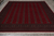 Hand-knotted Pakistani Bokhara rug lying flat on grey tile, orderly rows of octagonal guls
