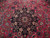 Close-up of black central medallion with 8 petal ivory rosette on raspberry red field