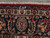 Woven signature cartouche in the navy top border of this signed Persian Mashad wool rug