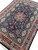 Angled floor view showing burgundy borders and ivory spandrels of this hand-knotted wool and silk rug