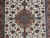 Close-up of teal and mauve central medallion surrounded by palmettes, rosettes and curling vines on ivory