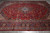 Angled overhead view of the all-over floral field, layered borders and cherry red ground