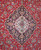 Close view of ivory and navy lobed medallion with 8 petal rosette on madder red ground