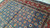 Floral lattice field meeting the red border, photographed in daylight on a smooth concrete floor