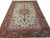 Ivory field Persian Tabriz rug with coral red floral border photographed against a white studio background
