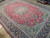 9'5" x 13'7" Persian rug photographed at an angle showing red field and indigo border depth