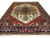 Ivory field Serapi rug with brick red spandrels and deep navy floral border, angled view