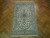 Hand-knotted Nain rug photographed on herringbone parquet floor showing ivory field and light blue guard borders
