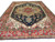Navy blue Serapi rug with brick red border and ivory corner spandrels shown at an angle