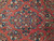 Close-up of hand-knotted floral sprays in navy, teal, cream and gold on red field