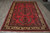 7x11 Sarouk rug laid flat on concrete floor showing cream border and red floral field