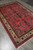 7'2" x 10'7" hand-knotted Persian wool rug seen from the corner with cream palmette border