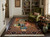 Rug on dark wood floor in a library setting with green wing chair, bookcases and pottery