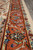Rust border detail with rosettes, sky blue blossoms and ivory vine scroll beside the selvage