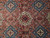 Close-up of hand-knotted wool pile showing ivory rosette medallion, blue diamonds and flowering vines