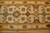 Close-up of beige field with slate blue diamonds, olive rosettes and rust gold multiple borders