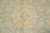 Close-up of wool pile showing gold vine scroll and small rosette on teal ground