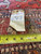 Original dealer tag reading 4.4 x 7 beside a tape measure on the woven end