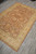 6x9 neutral wool area rug seen diagonally on grey plank floor with ivory fringe