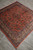Angled view of 6'8" x 6'8" Sarouk rug with navy outer border and coral field