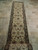 Extra long wool runner laid along travertine tile hallway, ivory field with near black floral border