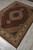 Oriental wool and silk rug displayed diagonally on grey tile, medallion and borders visible