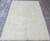Full view of the hand-knotted ivory Chobi rug resting on a red brick paver patio