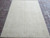 Angled 5x7 Peshawar Chobi wool rug showing cream field and faded all-over floral border