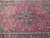 Close-up of the navy central medallion, pink palmettes and sage green leaves on red