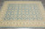 Angled overhead view of beige bordered blue lattice rug, hand-knotted natural wool pile