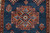 Rust latch-hook medallion with 8 petal rosette center set against abrashed denim blue wool field