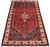 Angled view of 4'7" x 8' hand-knotted Persian village rug showing navy spandrels and red field