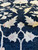 Detail of ivory leaf scrollwork and vine tracery woven across the black wool field
