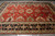 10' x 14' Serapi area rug on grey floor showing all-over geometric medallions in red
